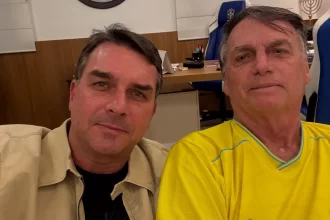 O senador Flávio Bolsonaro (PL-RJ) confirmou nesta sexta-feira, 5, que irá disputar a Presidência da República em 2026. O anúncio, feito por meio de publicação no X, movimentou o cenário político nacional e marca a entrada oficial do parlamentar na corrida ao Palácio do Planalto. Flávio Bolsonaro anuncia decisão e cita apoio de Jair Bolsonaro Segundo Flávio Bolsonaro, a candidatura foi motivada pela confiança e pelo aval de seu pai, o ex-presidente Jair Bolsonaro, atualmente preso na Superintendência da Polícia Federal em Brasília por ordem do ministro Alexandre de Moraes, do Supremo Tribunal Federal (STF). O senador declarou que recebeu a missão de dar continuidade ao projeto político que a família construiu nos últimos anos, ressaltando que pretende atuar para enfrentar o que chamou de instabilidade e insegurança no país. O presidente nacional do PL, Valdemar Costa Neto, já havia antecipado a escolha, afirmando que a decisão estava consolidada dentro da legenda. O dirigente reforçou que o partido seguirá unificado em torno da nova candidatura. Impactos da candidatura de Flávio Bolsonaro no cenário da direita A confirmação de Flávio Bolsonaro altera os arranjos internos da direita para 2026. A entrada do senador na disputa presidencial deve levar o governador de São Paulo, Tarcísio de Freitas, a concentrar esforços na própria reeleição, descartando uma eventual candidatura ao Planalto. A decisão também interfere nos planos eleitorais iniciais do próprio parlamentar. Até esta sexta-feira, Flávio era cotado pelo PL para disputar novamente o Senado pelo Rio de Janeiro. Com o partido decidindo apoiar a candidatura de Cláudio Castro ao cargo, abre-se espaço para novas articulações, como o interesse já manifestado pelo deputado Carlos Jordy. Trajetória política de Flávio Bolsonaro e o contexto envolvendo Jair Bolsonaro A candidatura de Flávio Bolsonaro surge em um momento em que Jair Bolsonaro permanece inelegível e cumprindo pena na PF. O ex-presidente foi condenado a 27 anos de prisão pela 1ª Turma do STF, em ação relacionada à suposta tentativa de golpe. Ele também se tornou inelegível em 2023, após decisão do Tribunal Superior Eleitoral. Foi da própria cela na PF que Jair Bolsonaro teria indicado Flávio como representante da família na disputa presidencial. Essa escolha marca uma mudança significativa, já que Jair concorreu nas últimas duas eleições, vencendo em 2018 e sendo derrotado em 2022 por Luiz Inácio Lula da Silva no segundo turno. Quem é Flávio Bolsonaro: trajetória até 2026 Natural do Rio de Janeiro, Flávio Bolsonaro tem 44 anos e iniciou sua vida pública em 2002, quando foi eleito deputado estadual pela primeira vez. Permaneceu na Alerj por quatro mandatos consecutivos. Em 2018, migrou para o Senado Federal, onde foi eleito com mais de 4 milhões de votos, o maior número registrado no estado naquela disputa. Sua atuação no Congresso e sua proximidade com o ex-presidente consolidaram sua influência dentro do PL. Com o anúncio, ele passa a integrar o grupo de pré-candidatos à Presidência em 2026. Além dele, já manifestaram interesse o atual presidente Lula, pelo PT; o governador de Minas Gerais, Romeu Zema (Novo); e o governador de Goiás, Ronaldo Caiado (União Brasil).